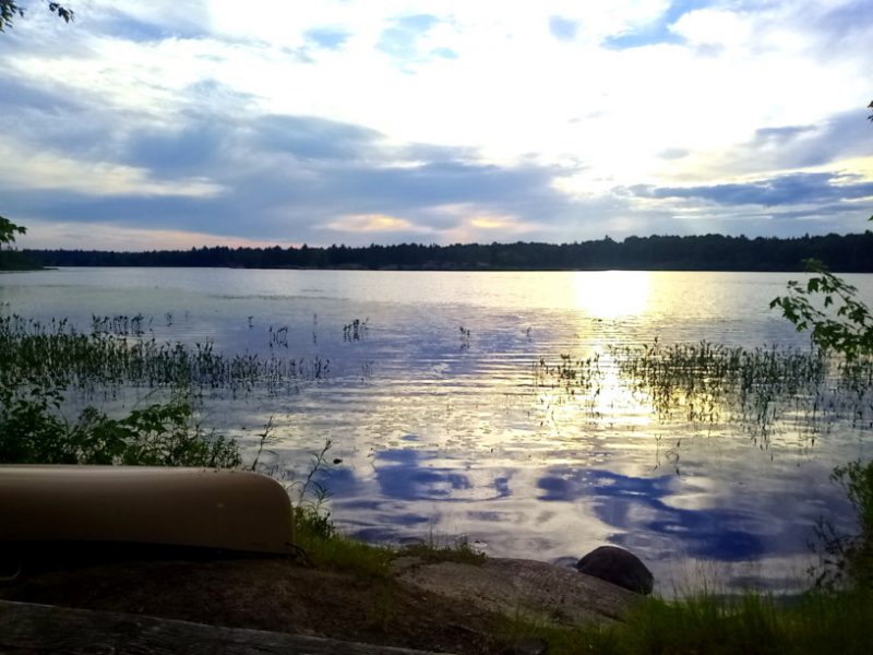 View of the lake from my campground on Pakeshkag Lake. Canoe on the shore, vibrant sky reflecting off the water.
